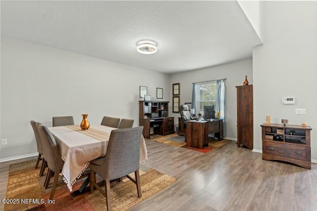 dining space with wood-type flooring and a textured ceiling