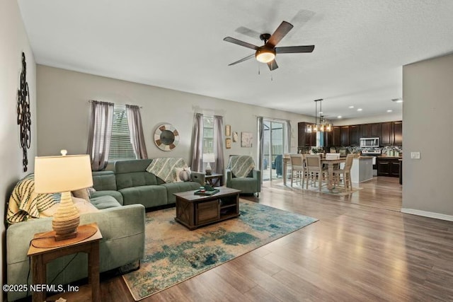 living room featuring ceiling fan with notable chandelier and light hardwood / wood-style flooring