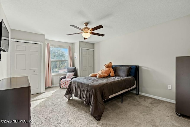 bedroom with ceiling fan, light colored carpet, and a textured ceiling