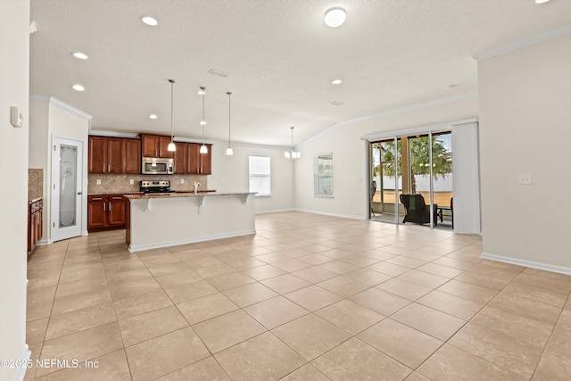 kitchen with a breakfast bar area, hanging light fixtures, light tile patterned floors, appliances with stainless steel finishes, and a kitchen island with sink