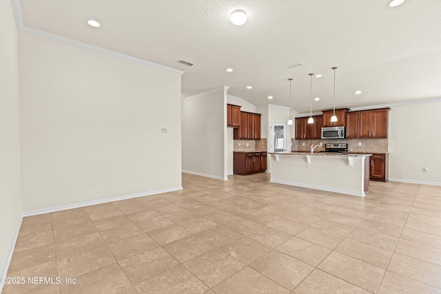 kitchen with decorative light fixtures, a breakfast bar area, stainless steel appliances, crown molding, and a center island with sink