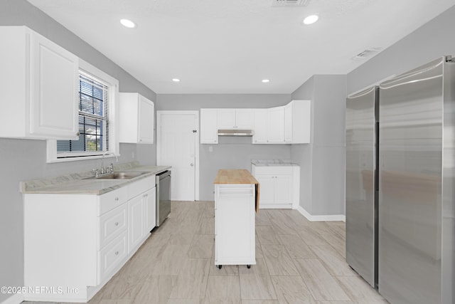 kitchen featuring stainless steel appliances, white cabinetry, sink, and wooden counters