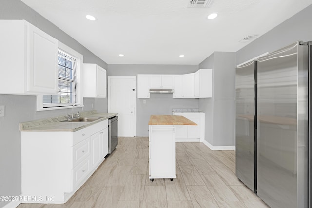 kitchen with wood counters, stainless steel appliances, white cabinets, and a kitchen island