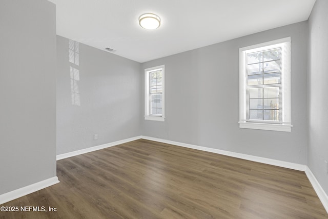 empty room with dark wood-type flooring and a healthy amount of sunlight