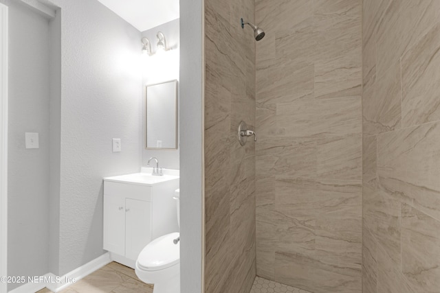 bathroom with vanity, a tile shower, and toilet