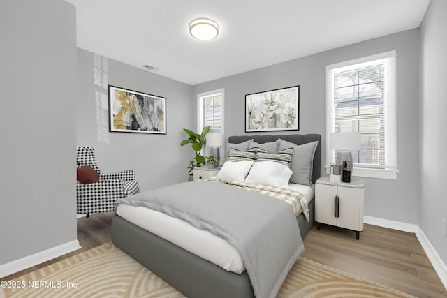 bedroom with hardwood / wood-style floors and multiple windows