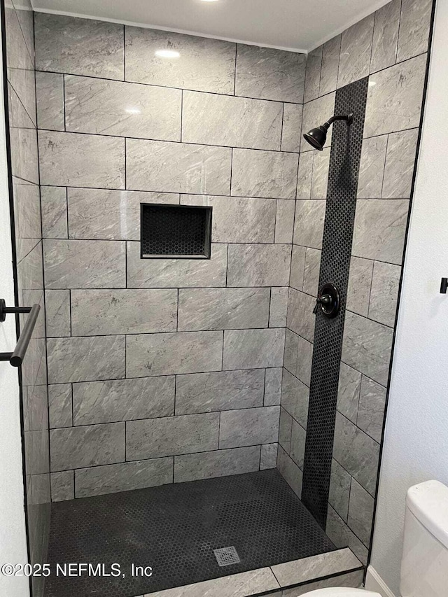 bathroom featuring tiled shower and toilet