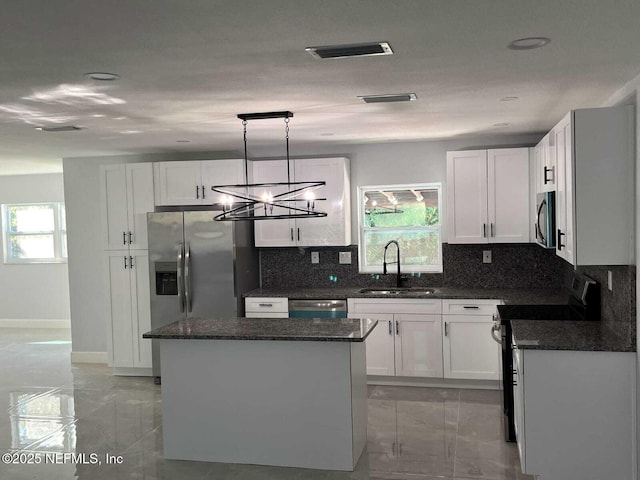 kitchen featuring stainless steel appliances, a center island, sink, and white cabinets