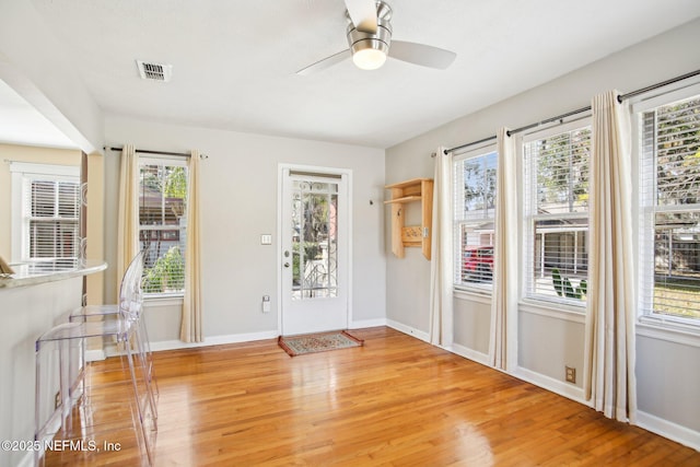 doorway with ceiling fan and light hardwood / wood-style flooring