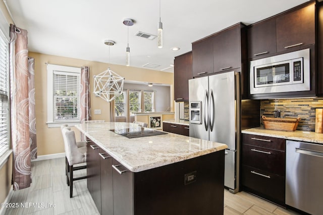 kitchen featuring hanging light fixtures, appliances with stainless steel finishes, a center island, and dark brown cabinetry