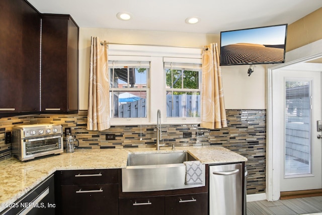 kitchen featuring light stone counters, dark brown cabinetry, and sink