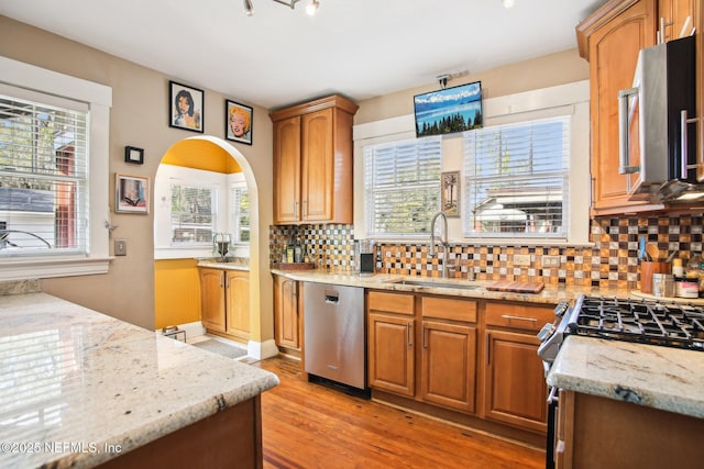 kitchen featuring light stone counters, sink, backsplash, and stainless steel appliances