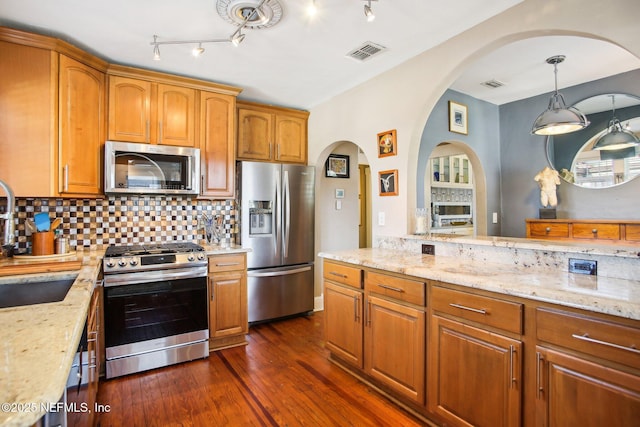 kitchen with pendant lighting, sink, stainless steel appliances, light stone countertops, and dark wood-type flooring