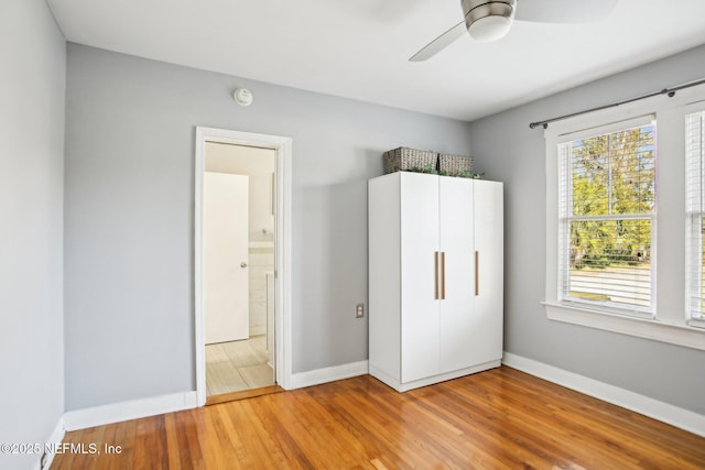 unfurnished bedroom featuring hardwood / wood-style flooring, connected bathroom, and ceiling fan