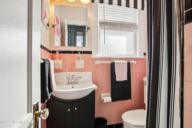 bathroom with vanity, toilet, and tile walls