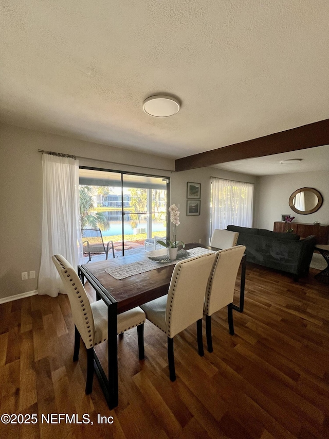 dining space with dark wood-type flooring, a wealth of natural light, and a textured ceiling