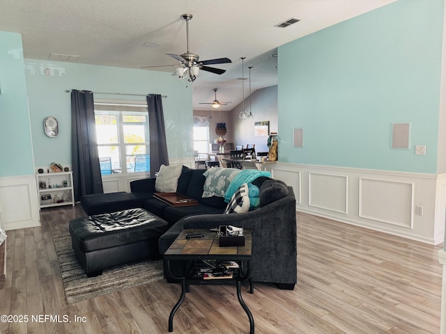 living room featuring lofted ceiling, light hardwood / wood-style flooring, and a textured ceiling