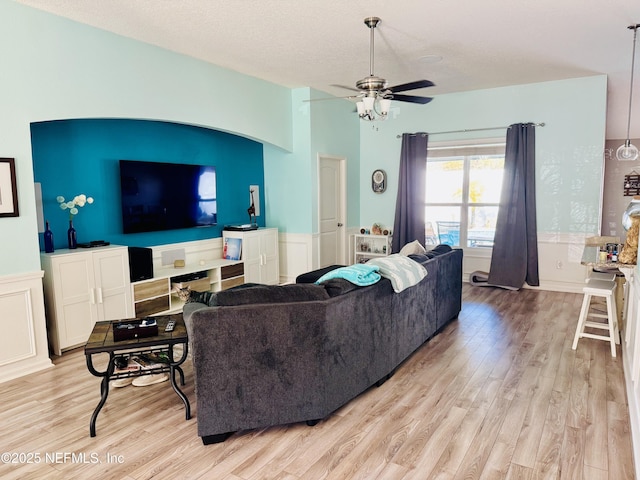 living room featuring ceiling fan, a textured ceiling, and light hardwood / wood-style floors