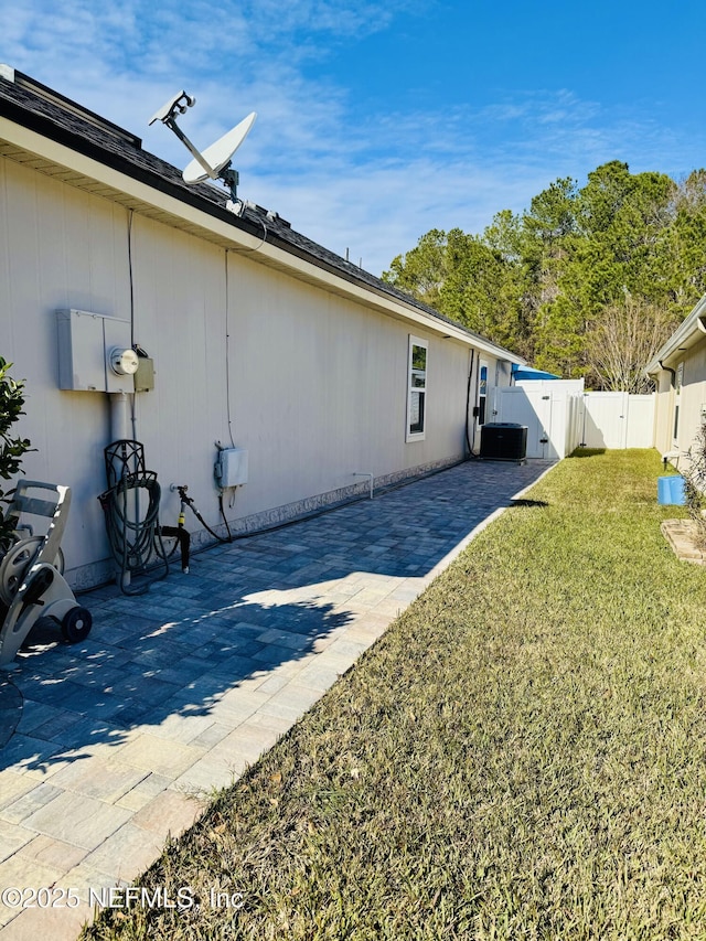 view of side of property with a yard, central AC unit, and a patio area