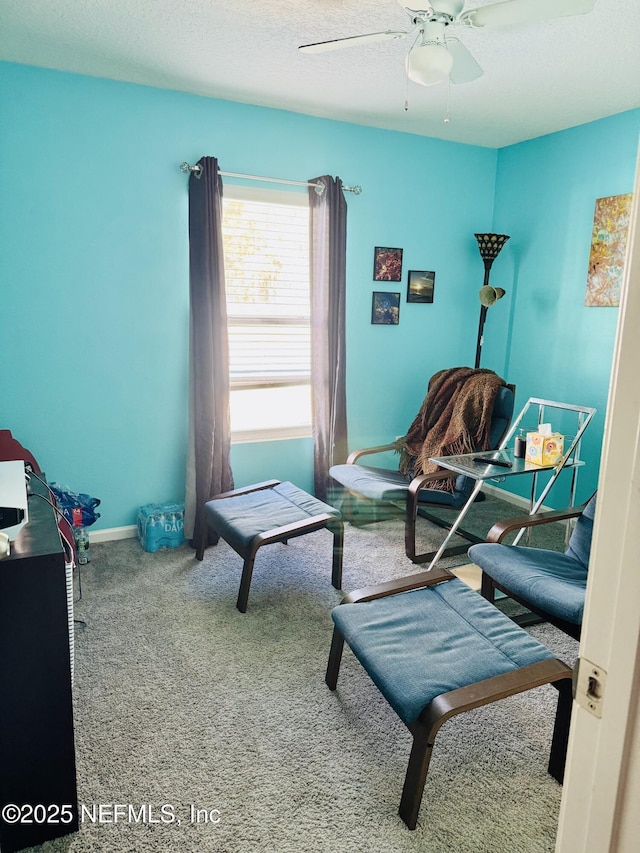 living area with a textured ceiling, carpet floors, and ceiling fan