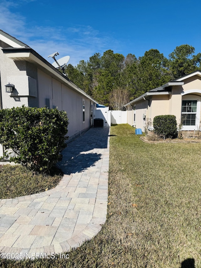 view of property exterior with a yard and central air condition unit