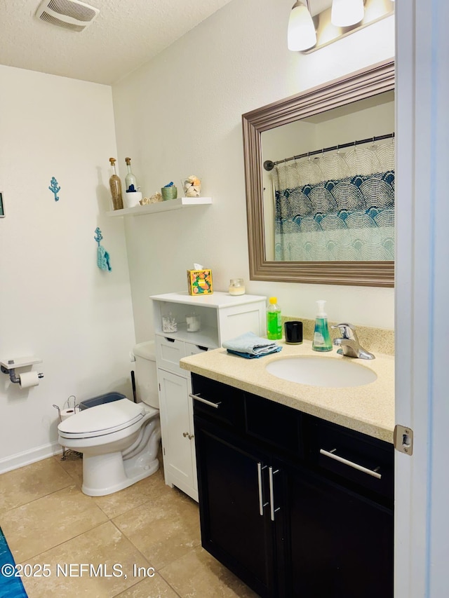 bathroom featuring tile patterned flooring, vanity, a textured ceiling, and toilet