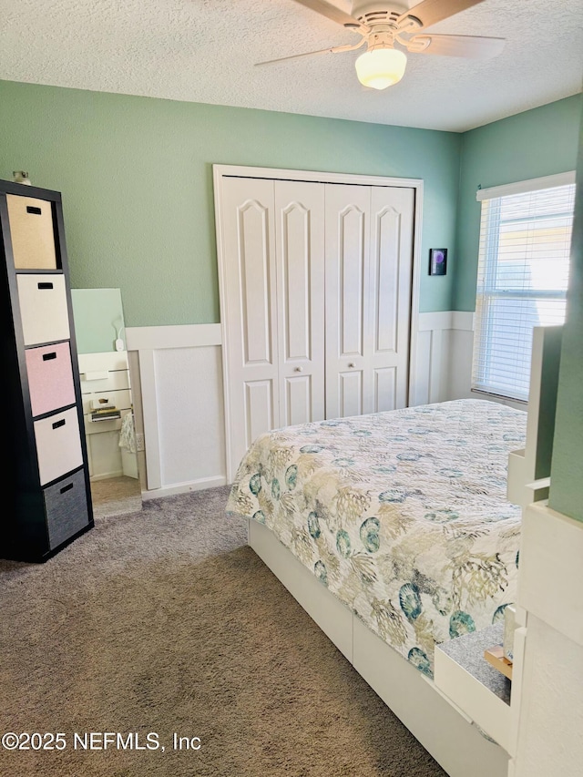 bedroom featuring ceiling fan, carpet floors, a closet, and a textured ceiling