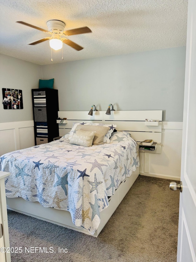 bedroom with ceiling fan, carpet, and a textured ceiling