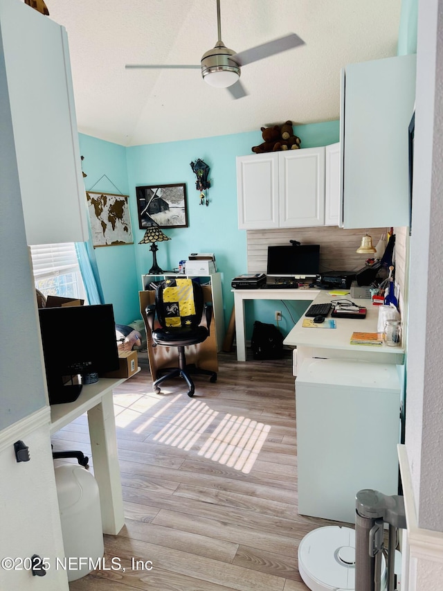 home office featuring ceiling fan, built in desk, and light hardwood / wood-style flooring