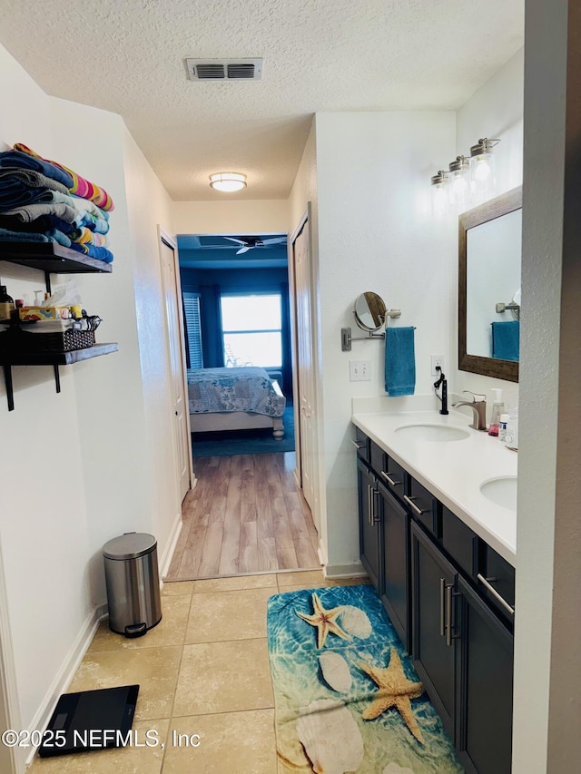 bathroom with tile patterned flooring, vanity, and a textured ceiling