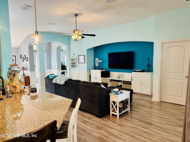 dining space featuring ceiling fan, vaulted ceiling, a textured ceiling, and light hardwood / wood-style flooring