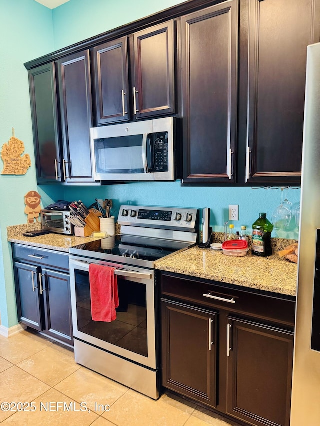 kitchen featuring stainless steel appliances, light tile patterned flooring, and light stone counters