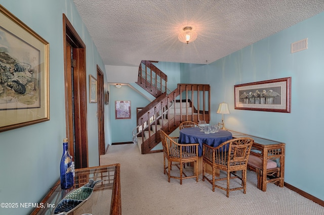 carpeted dining area with a textured ceiling