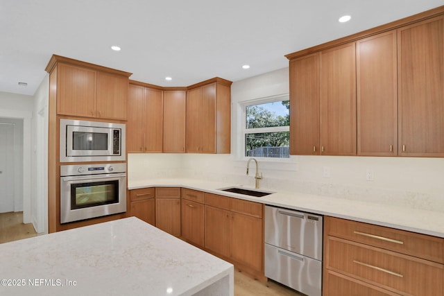 kitchen featuring sink, light wood-type flooring, light stone countertops, and appliances with stainless steel finishes