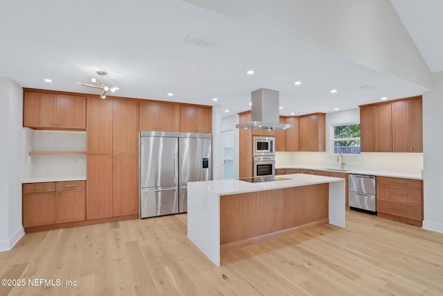 kitchen featuring sink, island exhaust hood, built in appliances, a kitchen island, and light wood-type flooring