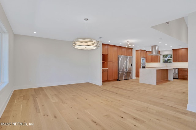 kitchen with built in appliances, a center island, light hardwood / wood-style flooring, pendant lighting, and island exhaust hood