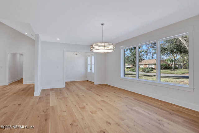 unfurnished dining area with vaulted ceiling and light hardwood / wood-style floors