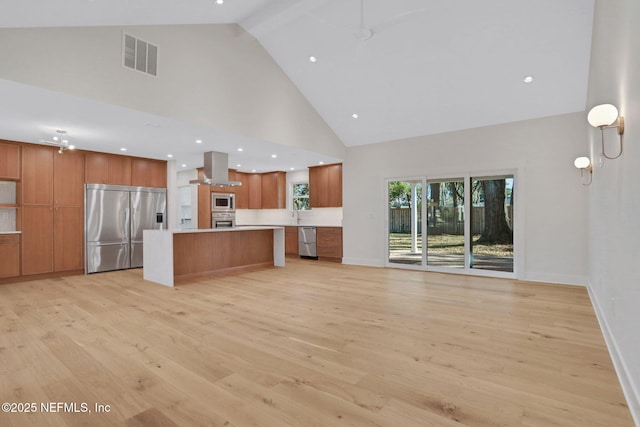 kitchen featuring light hardwood / wood-style flooring, high vaulted ceiling, a spacious island, built in appliances, and island exhaust hood