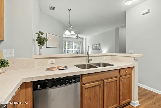 kitchen with pendant lighting, stainless steel dishwasher, sink, and light wood-type flooring