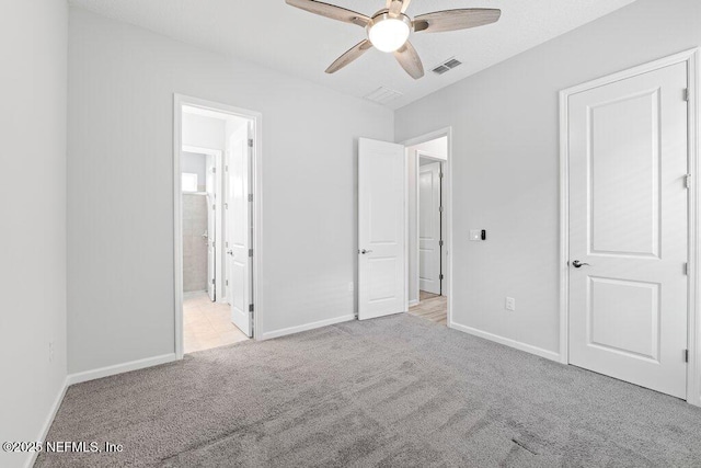 unfurnished bedroom featuring light colored carpet, ceiling fan, and ensuite bathroom