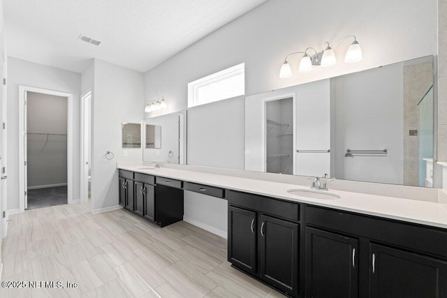 bathroom featuring vanity, a shower, and a textured ceiling