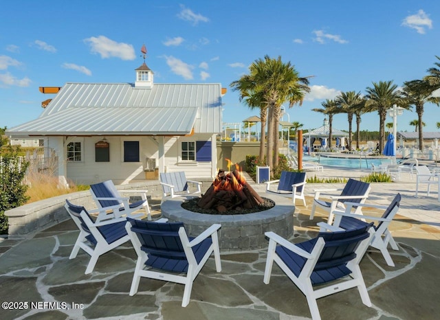 view of patio with a community pool and a fire pit