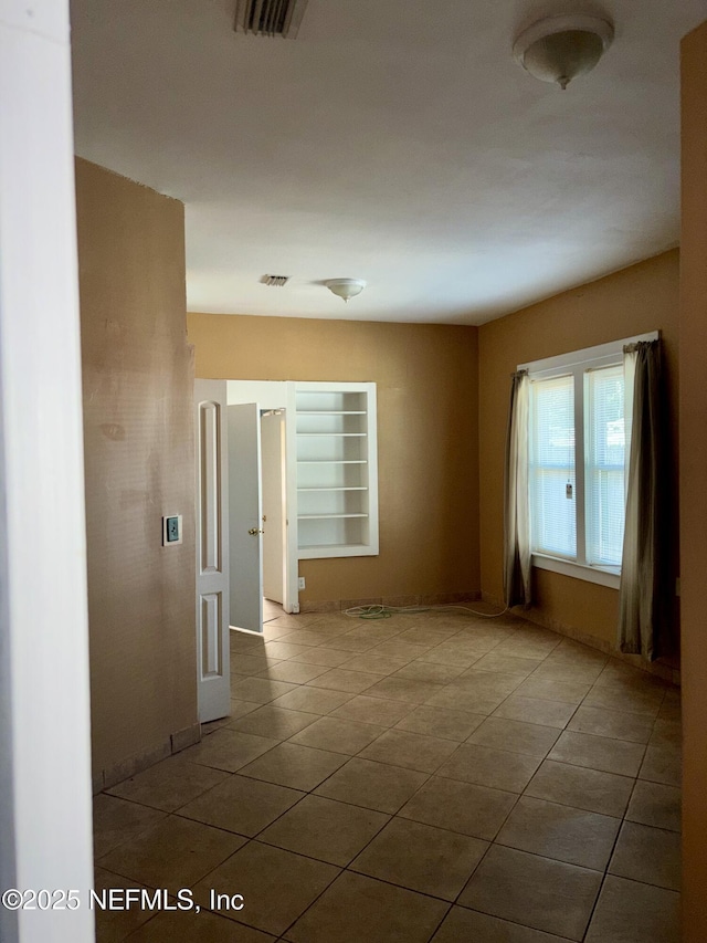 empty room with tile patterned floors and built in shelves