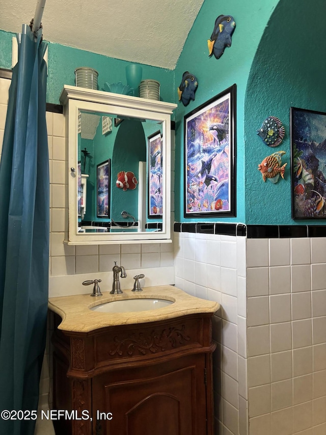 bathroom with tile walls, vanity, and a textured ceiling