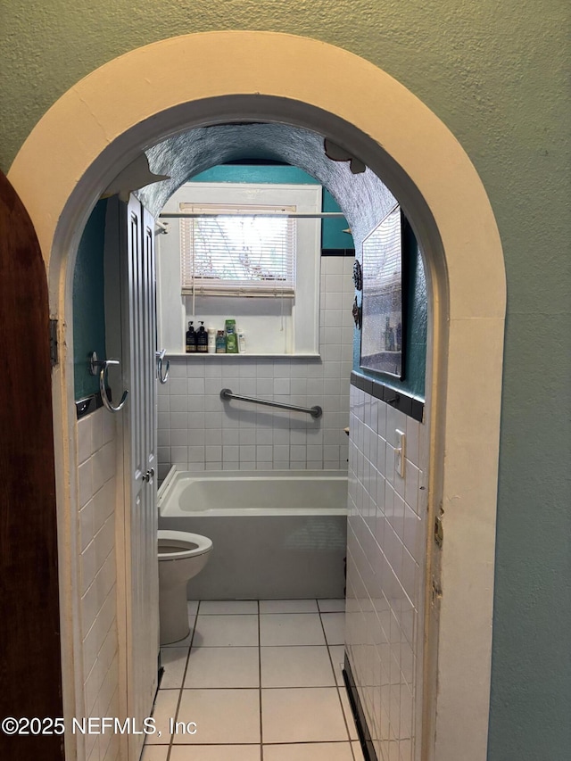 bathroom featuring tile patterned flooring, a washtub, and toilet