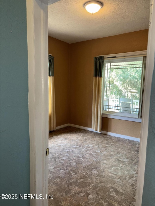 unfurnished room with a textured ceiling