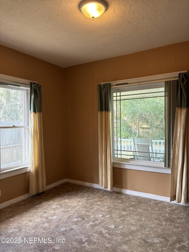 unfurnished room featuring plenty of natural light and a textured ceiling