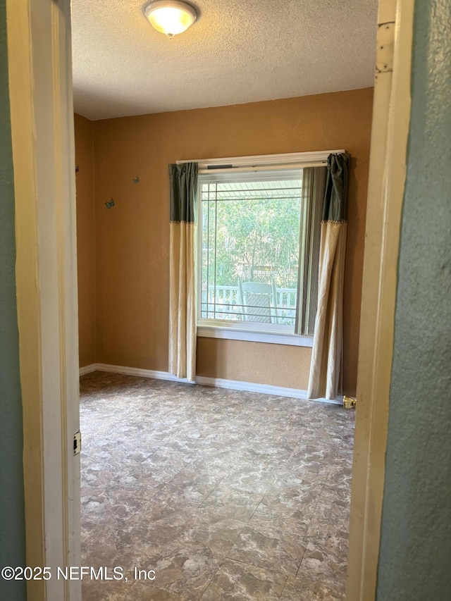 unfurnished room with a textured ceiling