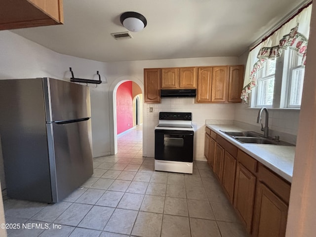 kitchen with tasteful backsplash, sink, stainless steel fridge, light tile patterned floors, and electric range