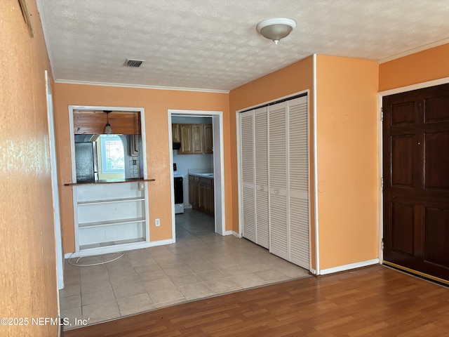 entrance foyer with crown molding, light hardwood / wood-style flooring, and a textured ceiling